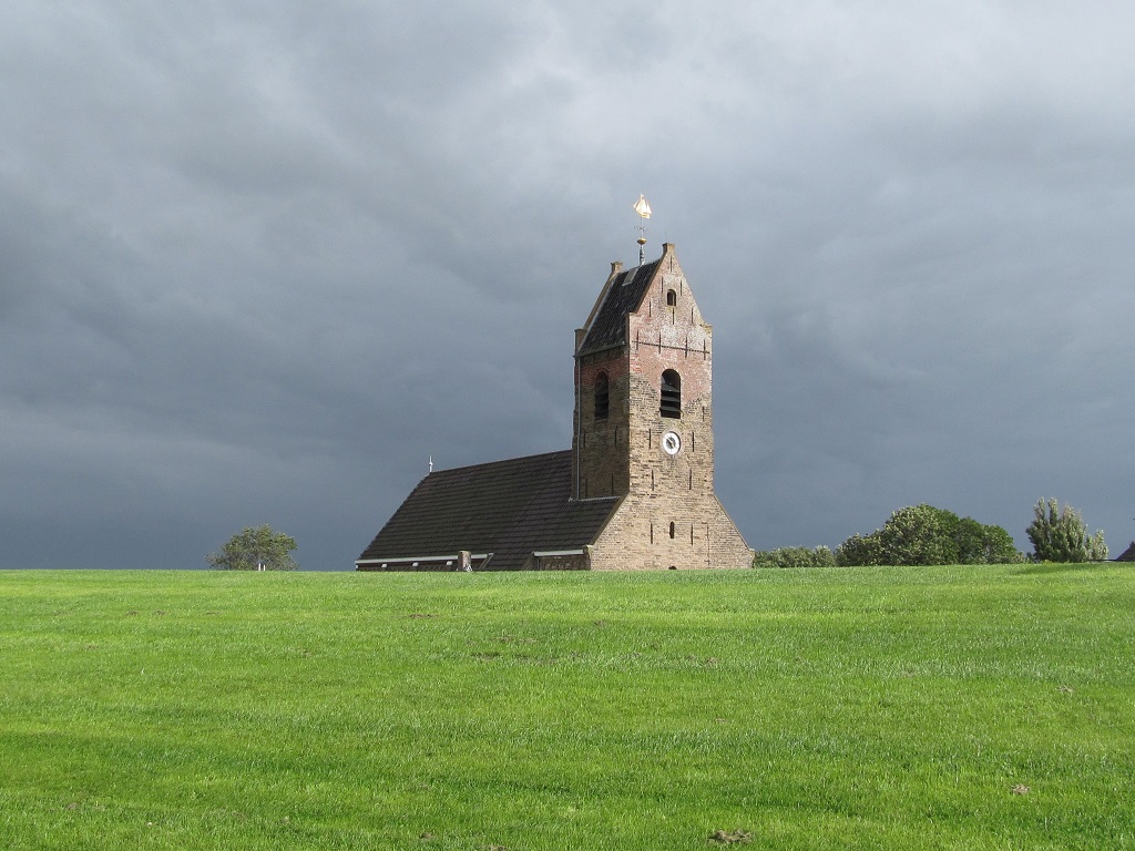 kerk torent boven de dijk uit in Wierum